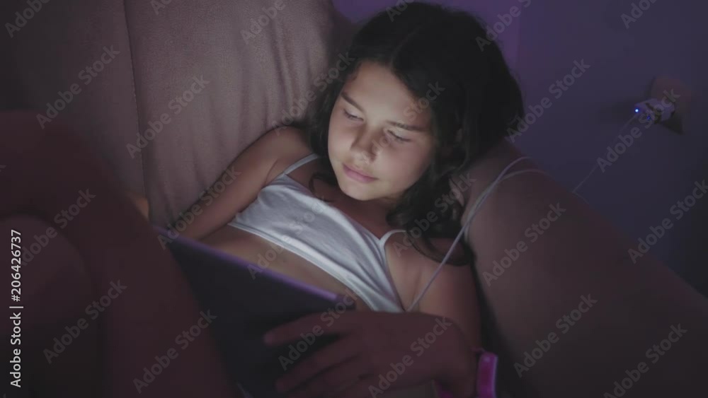 Vidéo Stock Little child girl using tablet at night. girl teen plays online the games social media. girl and tablet concept lifestyle | Adobe Stock