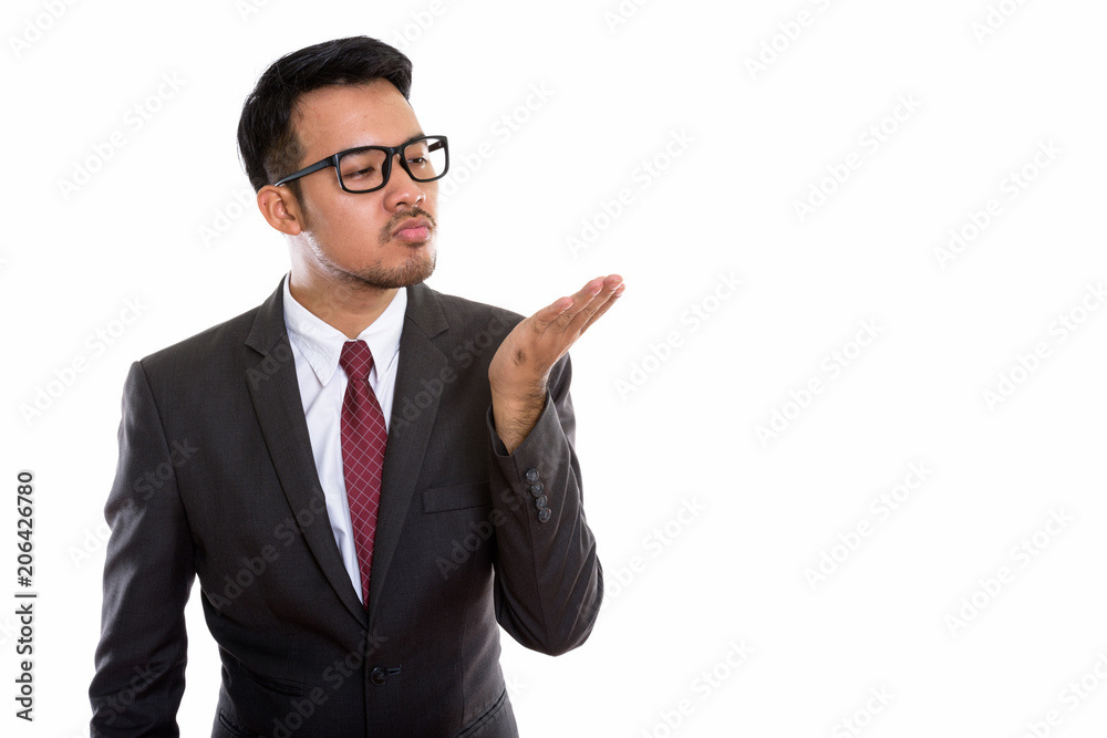 Studio shot of young Asian businessman giving flying kiss Studio shot of young Asian businessman giving flying kiss