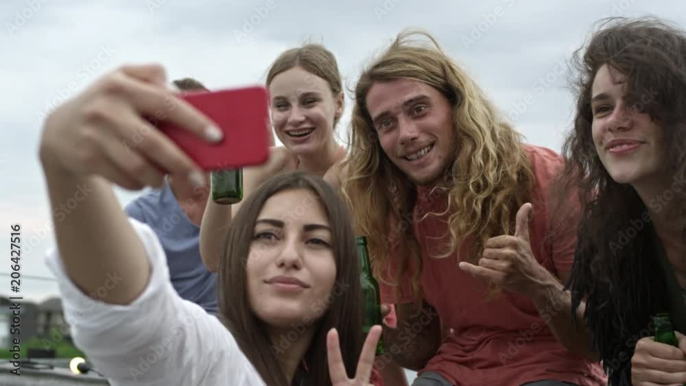 Group of friends holding bottles of beer and making faces when posing for smartphone camera for selfie Group of friends holding bottles of beer and making faces when posing for smartphone camera for selfie