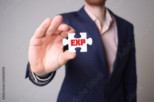 Businessman holding a puzzle with the inscription:EXP