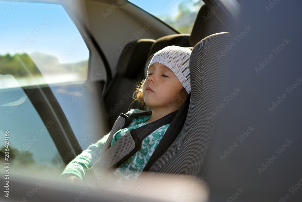 The child is in the car. Baby seat in the car. Little girl is sleeping in the car