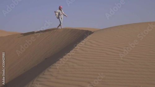 Girl teenager runs around the sand on the slope of the dune in Rub al Khali desert United Arab Emirates stock footage video photo