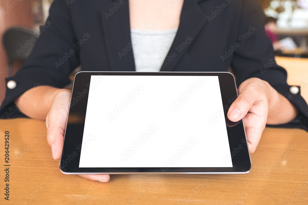 Mockup image of businesswoman holding and showing a black tablet pc with blank white desktop screen on table Mockup image of businesswoman holding and showing a black tablet pc with blank white desktop screen on table