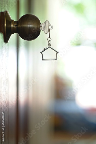 Home key with house keychain in keyhole, property concept