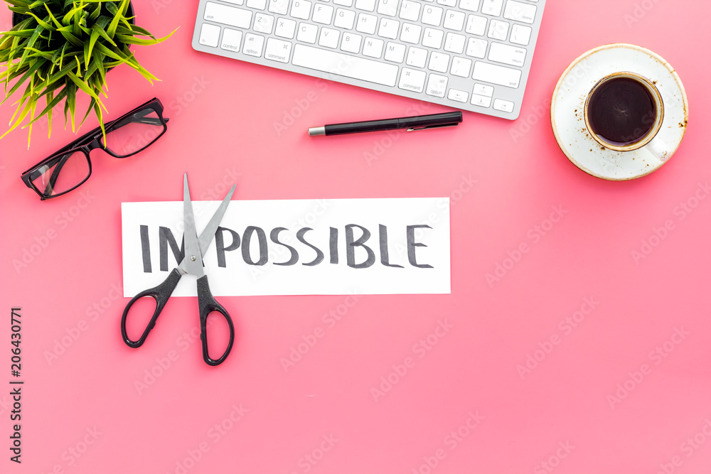 Make the impossible possible. Cutting the part im of written word impossible by sciccors. Office desk. Pink background top view copy space Make the impossible possible. Cutting the part im of written word impossible by sciccors. Office desk. Pink background top view copy space