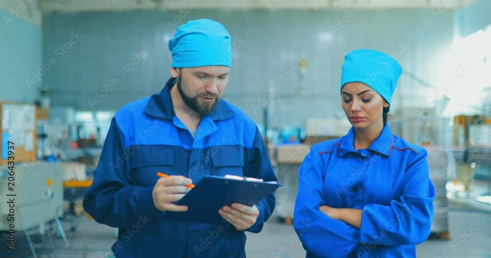 Workers at the factory of household chemicals, the production of liquid soap, going through the territory of an industrial enterprise and discussing something Workers at the factory of household chemicals, the production of liquid soap, going through the territory of an industrial enterprise and discussing something