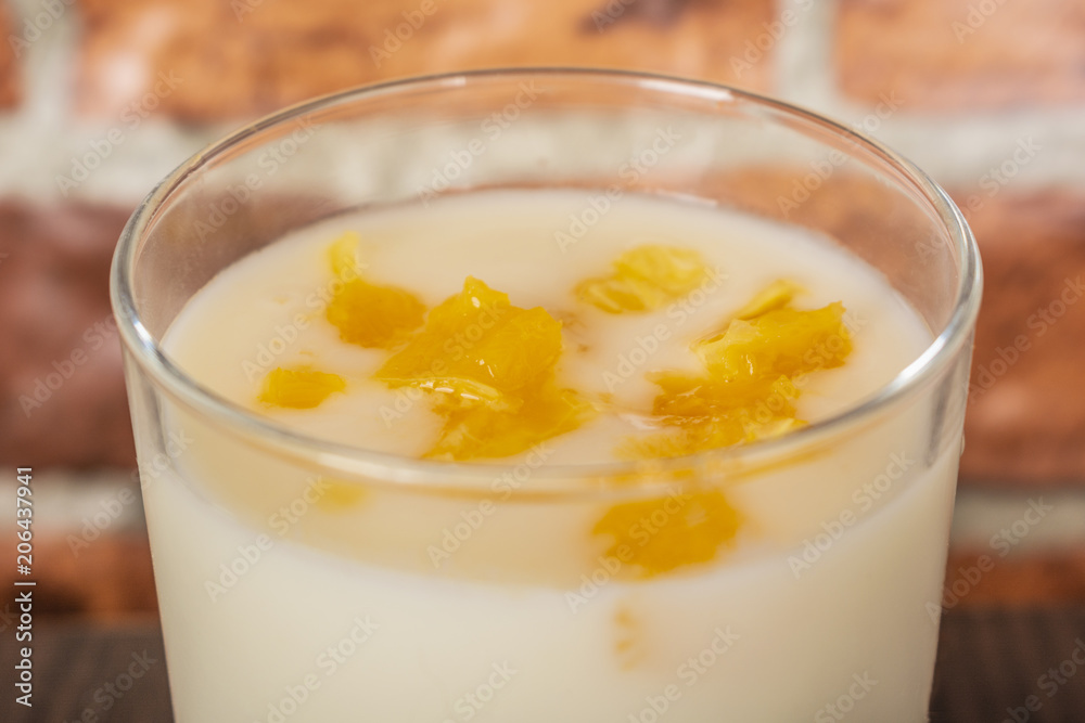 yogurt with orange jam in a glass cup on a rustic wooden table on a brick wall background yogurt with orange jam in a glass cup on a rustic wooden table on a brick wall background