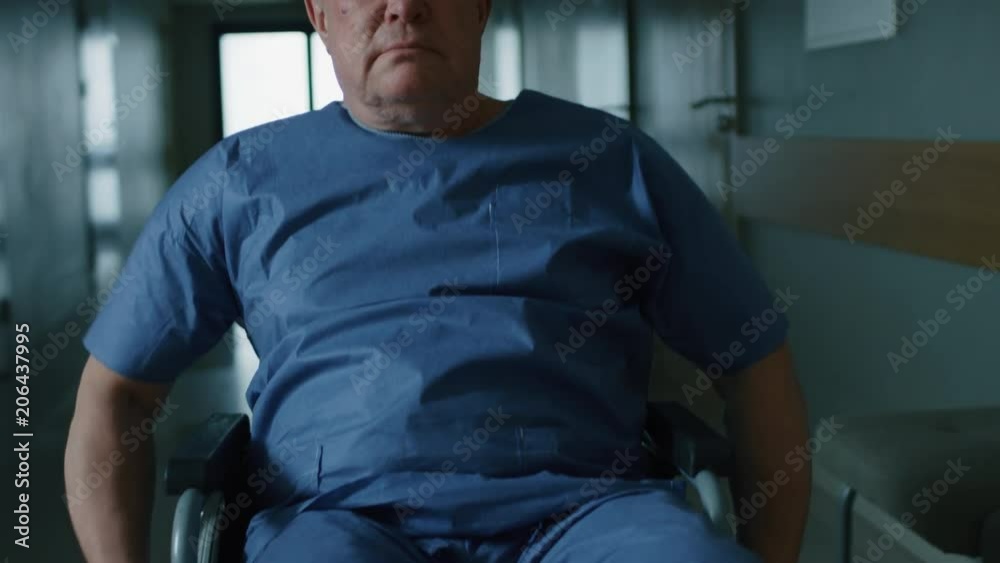 In the Hospital, Back View Following Shot of the Elderly Man in the Wheelchair Moving through the Hallway. Shot on RED EPIC-W 8K Helium Cinema Camera. In the Hospital, Back View Following Shot of the Elderly Man in the Wheelchair Moving through the Hallway. Shot on RED EPIC-W 8K Helium Cinema Camera.