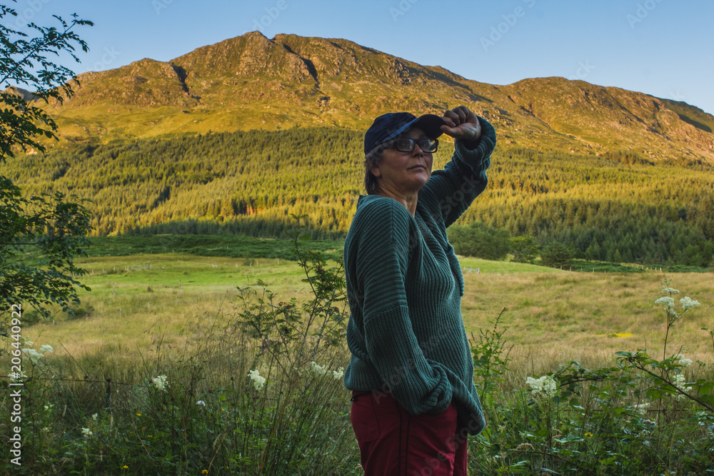Middle age woman wearing wool sweater, cap and glasses happy and