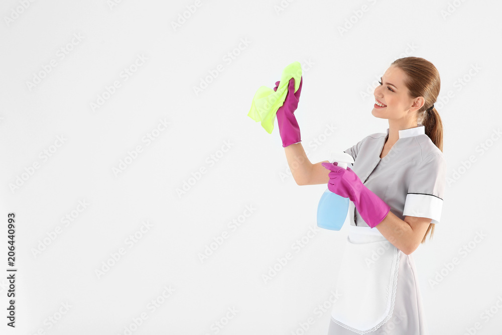 Young chambermaid with rag and detergent on white background Young chambermaid with rag and detergent on white background
