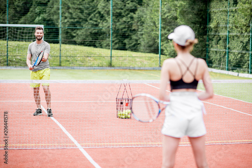Young couple in white sports wear playing tennis on the tennis court outdoors © rh2010