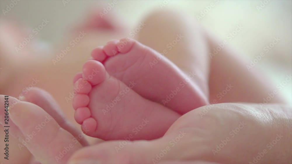 Baby feet in parent's hands. Tiny newborn baby's feet on hands closeup. Happy family concept. Slow motion. 3840X2160 4K UHD video footage Baby feet in parent's hands. Tiny newborn baby's feet on hands closeup. Happy family concept. Slow motion. 3840X2160 4K UHD video footage