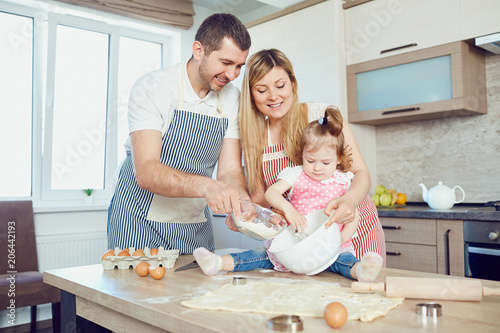 A happy family prepares baking in the kitchen.