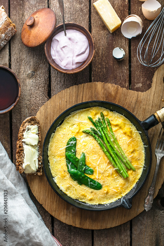 Frittata with green asparagus, pea on frying pan, top view, rustic style