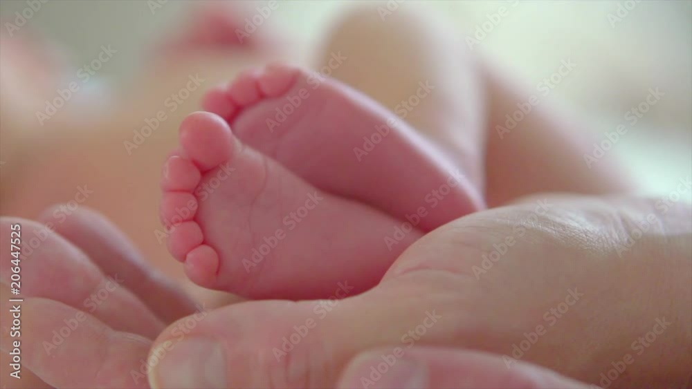 Baby feet in parent's hands. Tiny newborn baby's feet on hands closeup. Happy family concept. Slow motion. 3840X2160 4K UHD video footage Baby feet in parent's hands. Tiny newborn baby's feet on hands closeup. Happy family concept. Slow motion. 3840X2160 4K UHD video footage