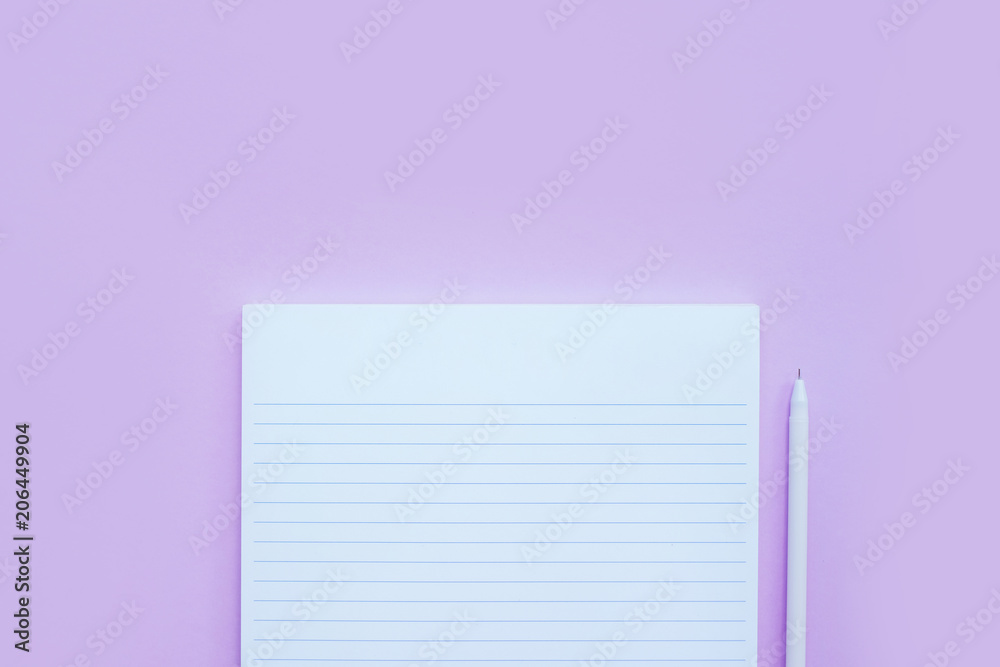 Beautiful office stationery flatlay with ruled notebook, pen, sticky note and paper clip on the bright desk with violet background.