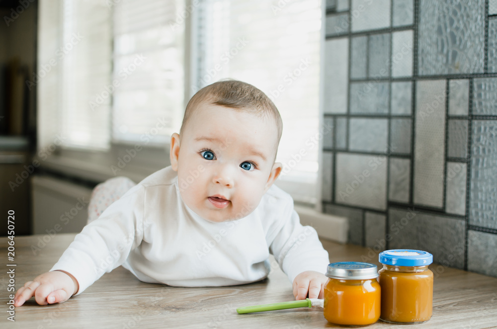 baby with blue eyes crawling, wants to eat pumpkin puree in a jar baby with blue eyes crawling, wants to eat pumpkin puree in a jar