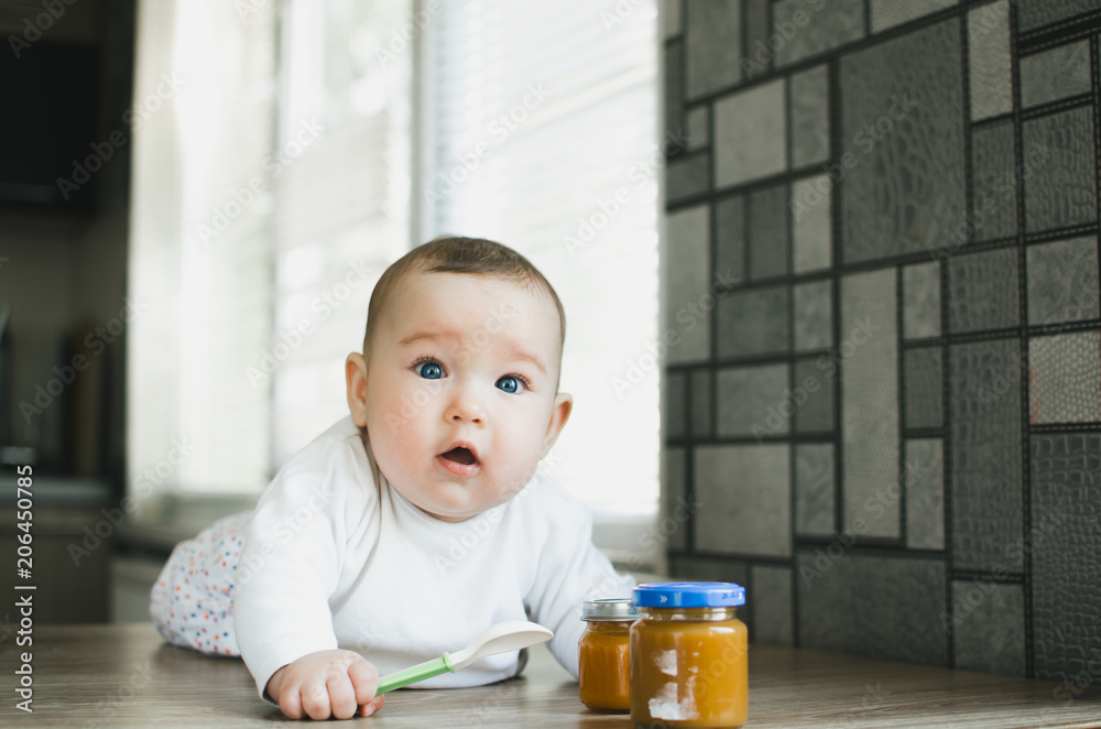 baby with blue eyes crawling, wants to eat pumpkin puree in a jar baby with blue eyes crawling, wants to eat pumpkin puree in a jar