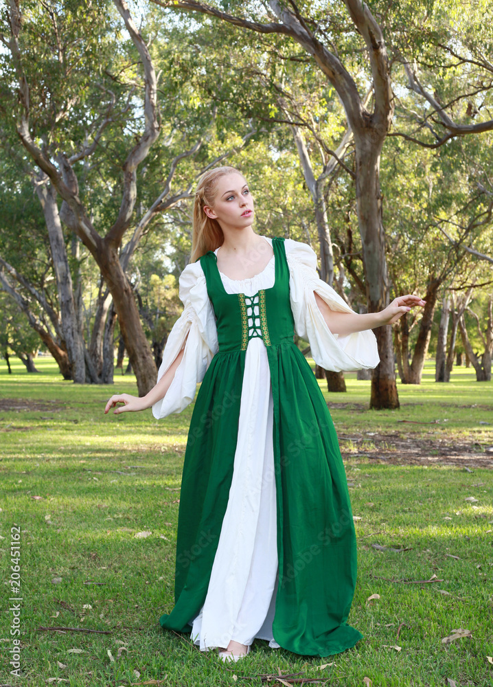 full length portrait of blonde girl wearing greensand white medieval costume, standing pose. walking through a forest. full length portrait of blonde girl wearing greensand white medieval costume, standing pose. walking through a forest.