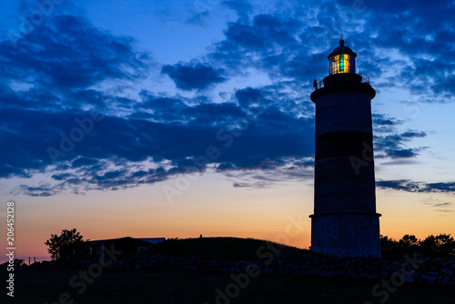 Lighthouse shining its light at twilight just after sunset. Location Morups Tange in Falkenberg, Sweden.