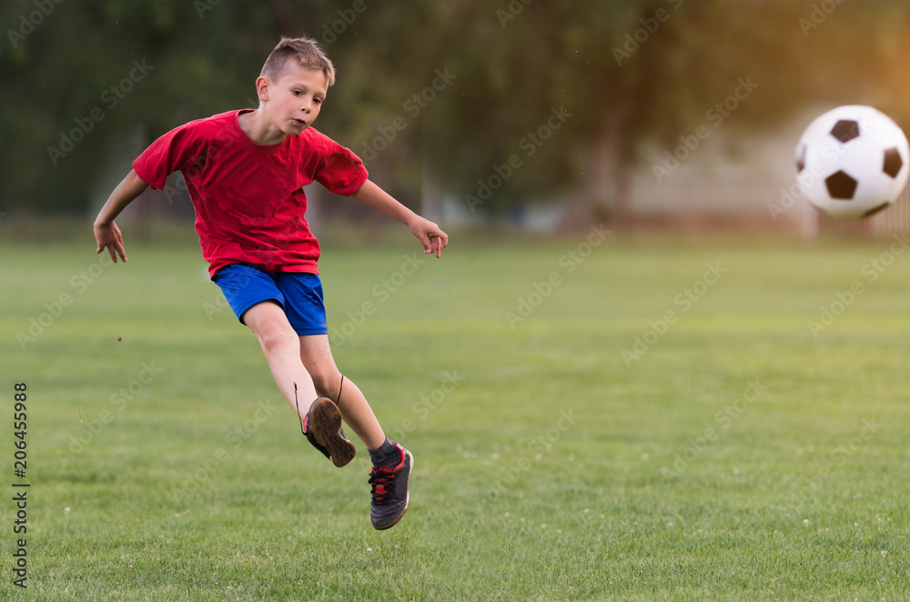 Boy kicking football on the sports field Boy kicking football on the sports field