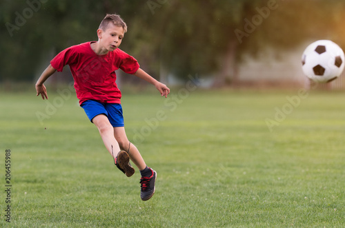 Fototapeta Naklejka Na Ścianę i Meble -  Boy kicking football on the sports field