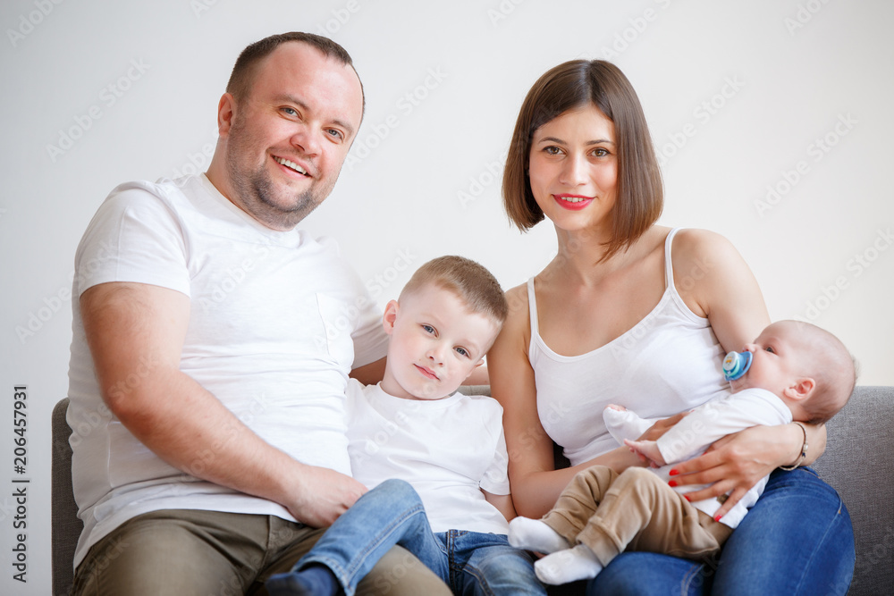 Picture of happy married couple with two young sons sitting on sofa Picture of happy married couple with two young sons sitting on sofa