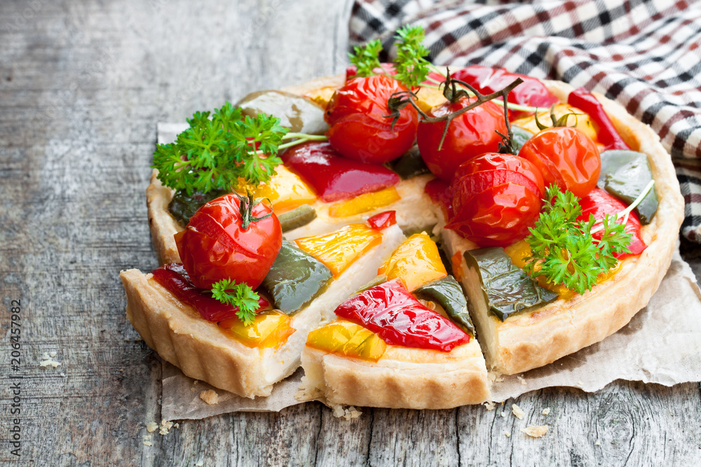 Vegetarian  quiche with colored pepper and cherry tomatoes on wooden table