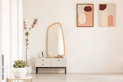 Canvastavla Plant on table and mirror on white cabinet in simple living room interior with posters