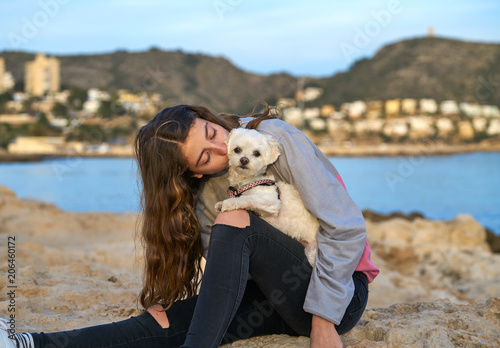 Girl playing with maltichon dog in the beach