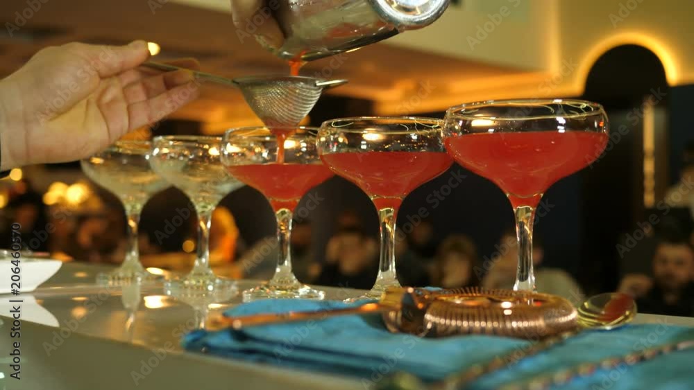 Preparation of a cocktail in five glasses based on cherry syrup, the barman pours a cooked cocktail in a shaker, soft cocktails, a barman show, a barmen competition, a healthy lifestyle, a healthy
