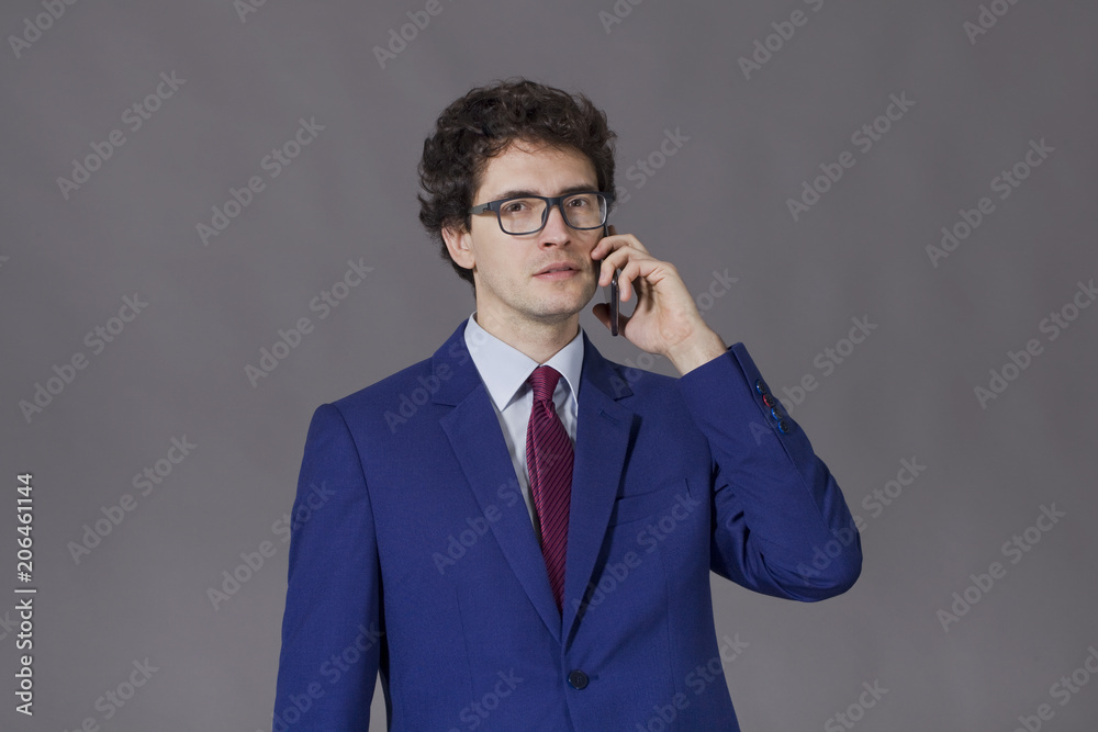 Guy with good blue suit and glasses talking by phone Guy with good blue suit and glasses talking by phone