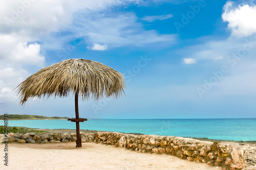 Palm leaf beach umbrella on a deserted shore