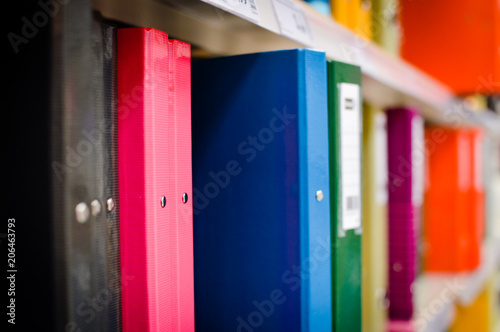 Close up on multicolored office folders on the bookshelf backgrounds. Many working stationery, stacked records. Different color spectrum documents. Educational or financial file-box object supplies