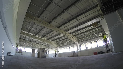 Construction, installing ceiling tiles to the grid in large area photo