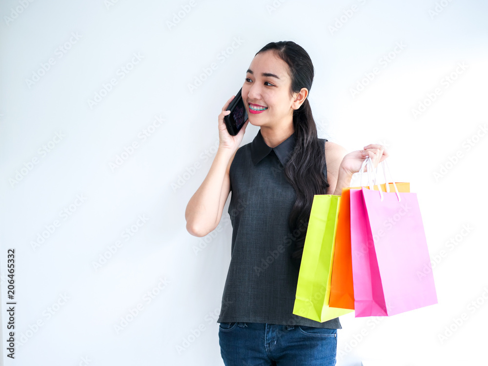 Happy Asain woman talking on phone and holding shopping bag,shopping concept. Happy Asain woman talking on phone and holding shopping bag,shopping concept.