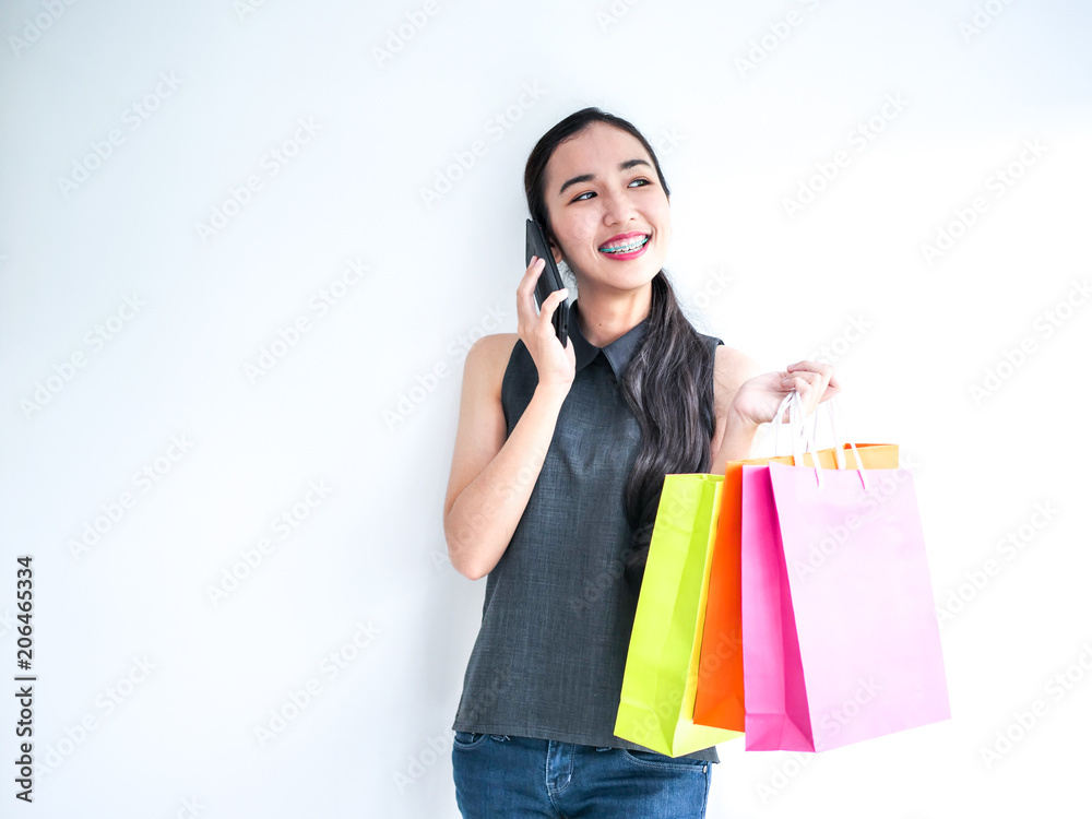 Happy Asain woman talking on phone and holding shopping bag,shopping concept. Happy Asain woman talking on phone and holding shopping bag,shopping concept.