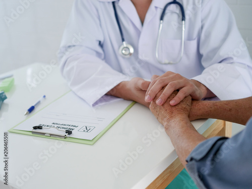 Close up doctor hands hoilding Elderly woman hands in hospital with doctor. photo