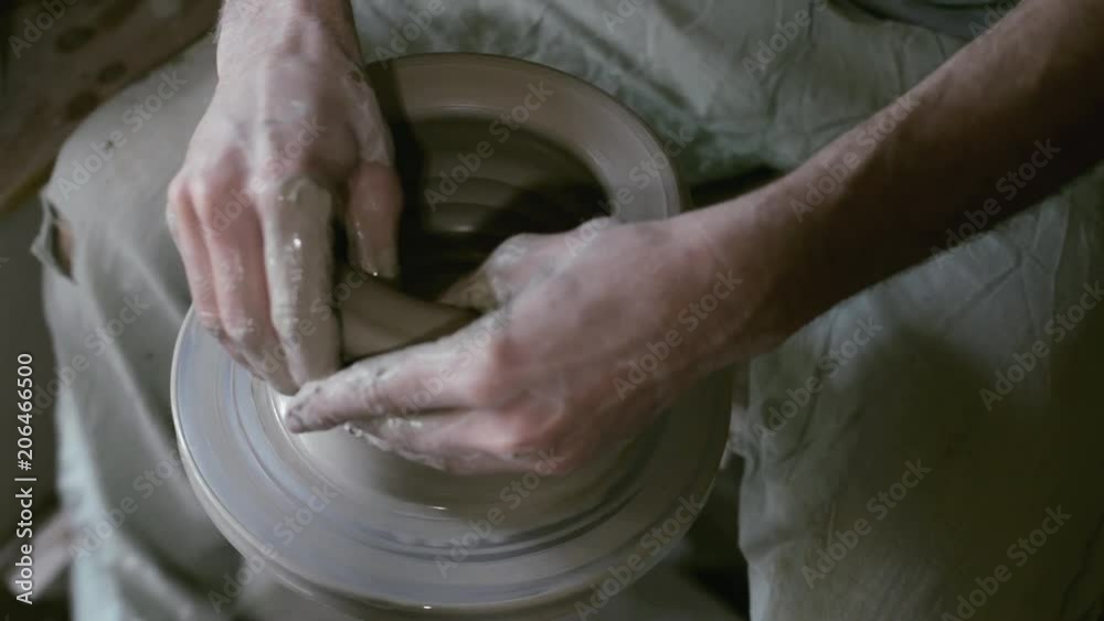 Potter rises of pot on rolling potter's wheel by wet hands Potter rises of pot on rolling potter's wheel by wet hands