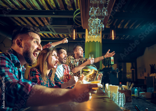 Sport  people  leisure  friendship and entertainment concept - happy football fans or male friends drinking beer and celebrating victory at bar or pub