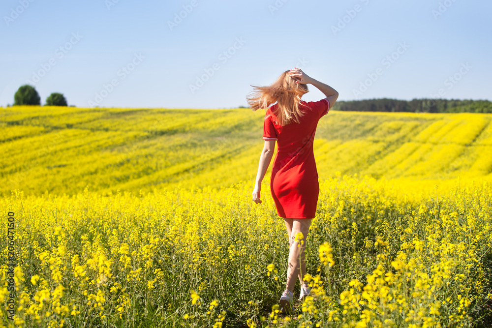 Fototapeta premium Young woman cheering in the rape seed field