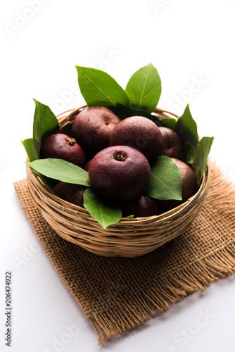 Fresh Kokum or Garcinia indica fruit from India isolated over white or in cane basket with leaves. selective focus photo