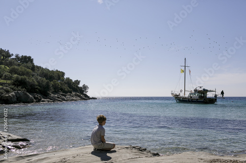 Boy sitting at seaside looking at view