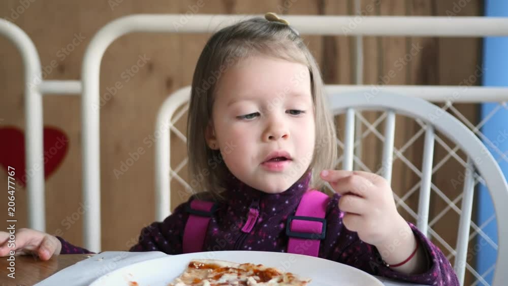In restaurant pizzeria cute little kid girl portrait eating chewing pizza with fingers
