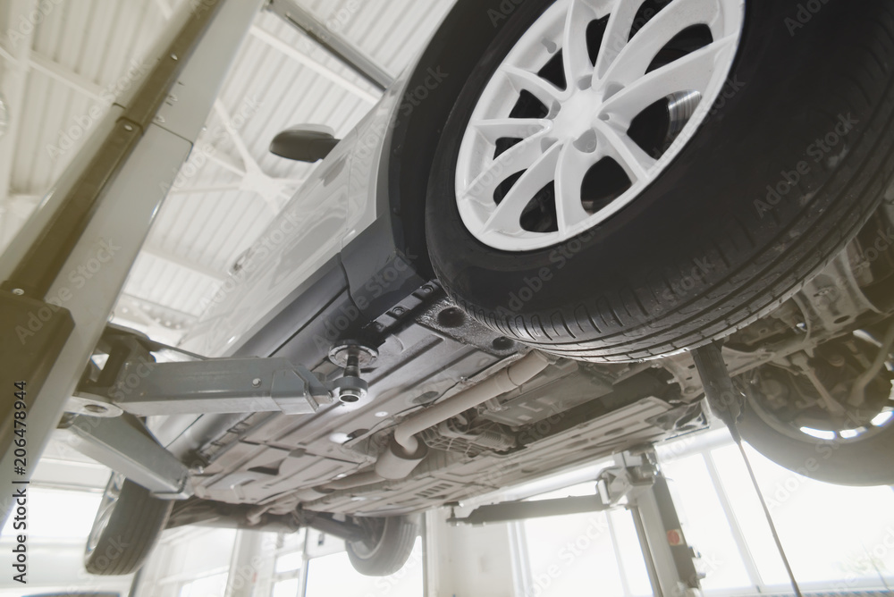 Car on a wheel alignment lift in auto service. Diagnosis of the chassis of the car raised at the elevator. toning