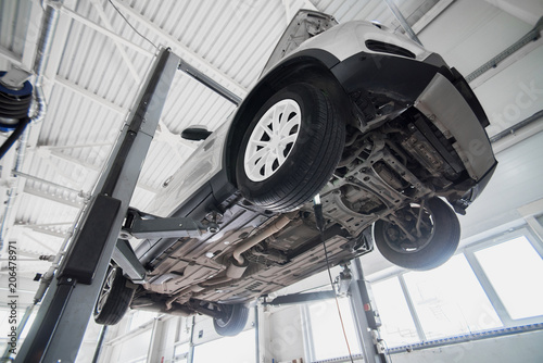 Car on a wheel alignment lift in auto service. Diagnosis of the chassis of the car raised at the elevator.