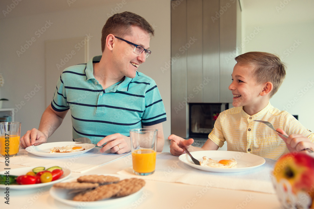 Happy young father with his cute son talking at the breakfast Happy young father with his cute son talking at the breakfast