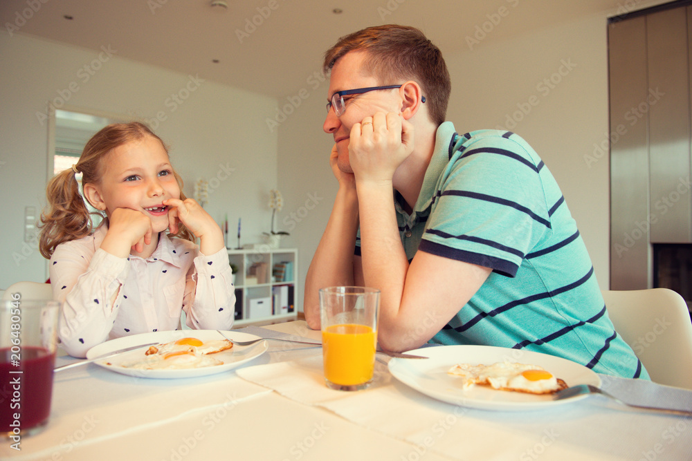 Happy father with his children talking at the breakfast at home