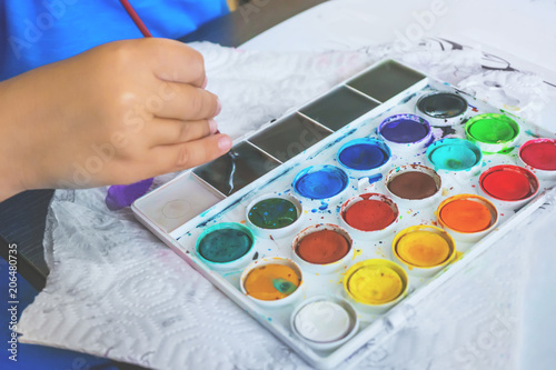Close-up of a small child draws colored paint gouache