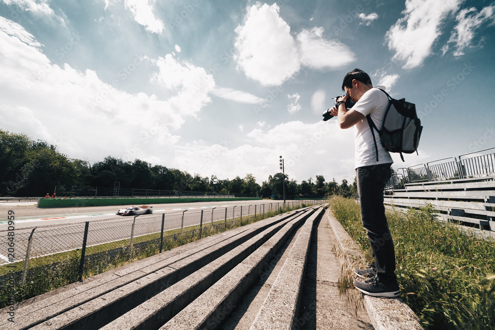 Amateur photographer taking photo to a sport car during racing cars - wide angle view